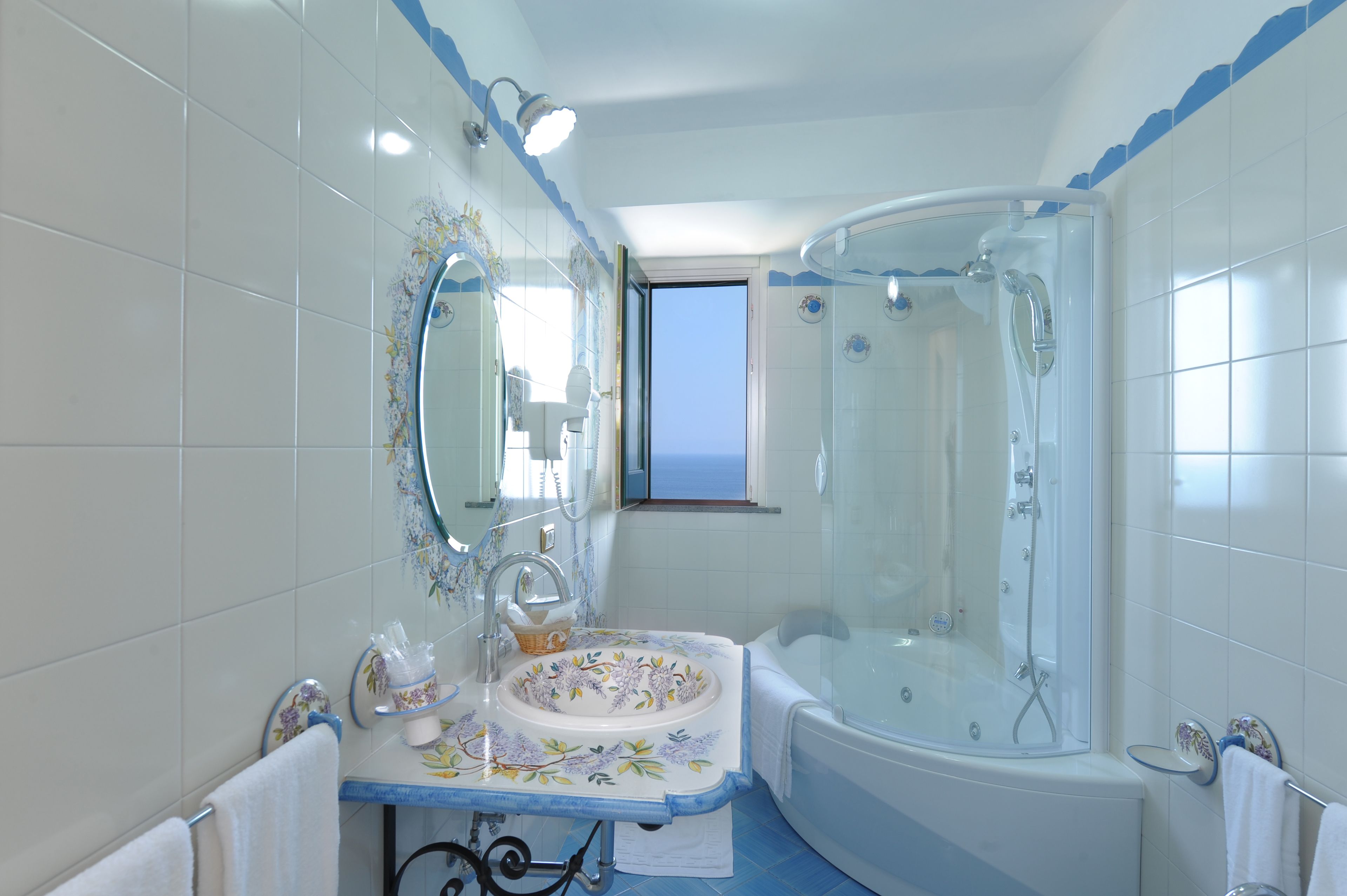 A bathroom with a bathtub, a sink with a floral design, and a shower area.