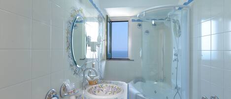 A bathroom with a bathtub, a sink with a floral design, and a shower area.