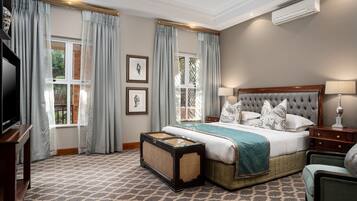 A bedroom with a large bed, a television, and a window with curtains.