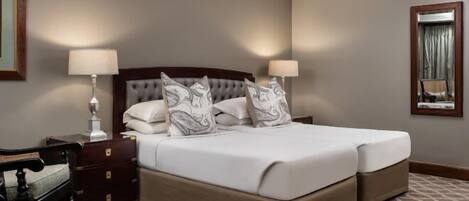 Una habitación de hotel con una cama grande, dos lámparas de noche, una mesita de madera y un espejo en la pared.