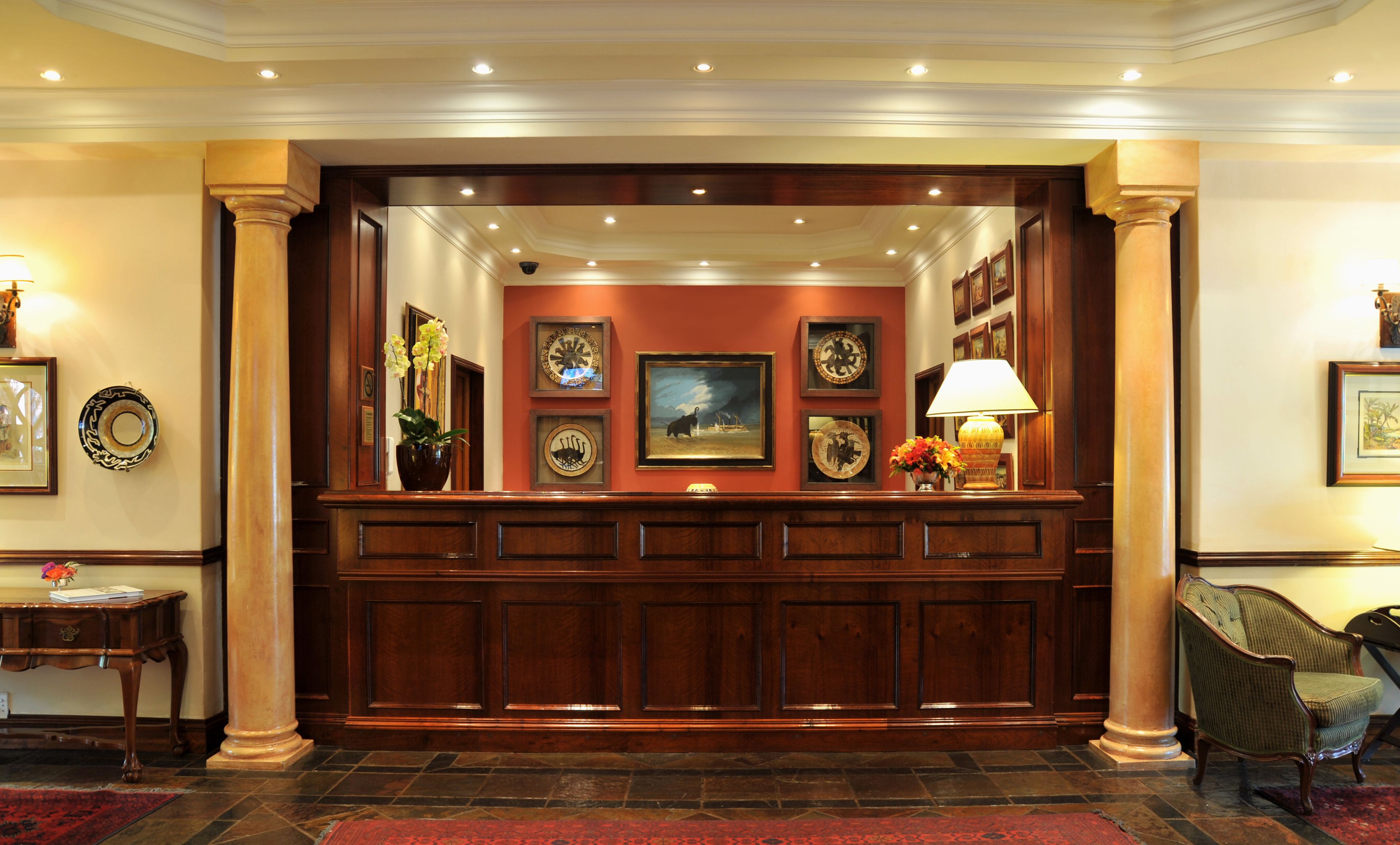 A reception area with a wooden reception desk, framed artwork on the walls, and a red carpet.
