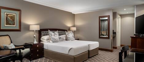 A hotel room with a large bed, a desk, a chair, a television, and a mirror.
