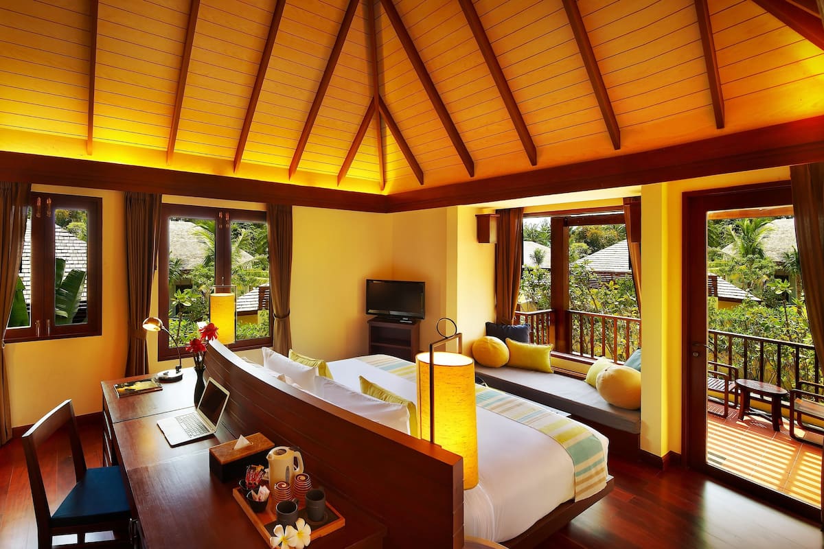 A hotel room with a bed, desk, and balcony.