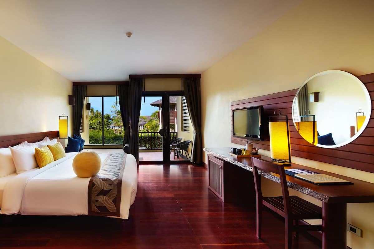 A hotel room with a bed, bedside table, desk, chair, and a large mirror.