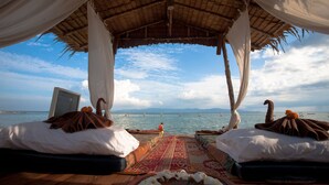 Una cama frente a la playa con vistas al mar y las montañas.