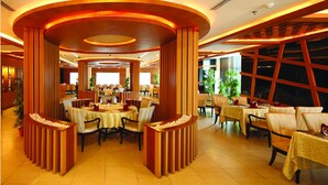 A restaurant with round tables, wooden columns, and a warm, inviting atmosphere. - Windsor Rajadhani (Thiruvananthapuram)