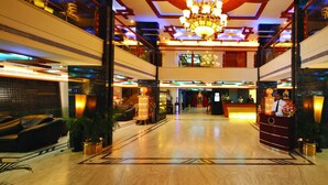 A spacious lobby with a reception desk, leather sofas, and a chandelier. - Windsor Rajadhani (Thiruvananthapuram)