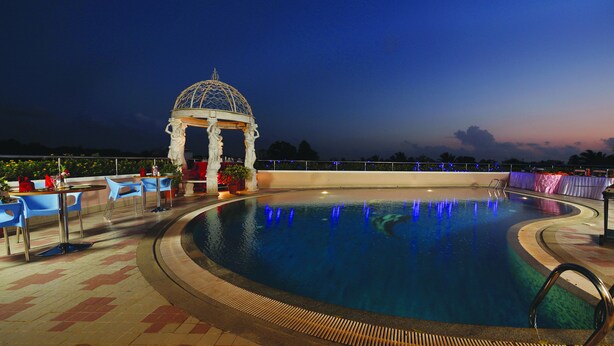 A pool area with a gazebo, outdoor seating, and a chef preparing food. - Windsor Rajadhani (Thiruvananthapuram)