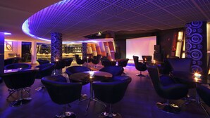 A modern lounge area with black leather chairs, a bar, and a ceiling with a grid pattern. - Windsor Rajadhani (Thiruvananthapuram)