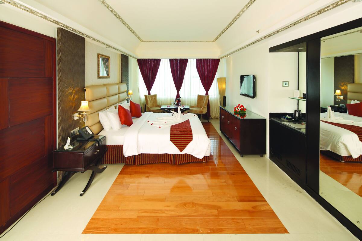A spacious hotel room with a large bed, a desk, a chair, and a television.