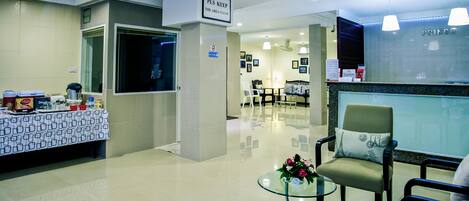 Een schone, moderne lobby met een receptiebalie, een zithoek en een bordje met de tekst 'Area schoonhouden'.
