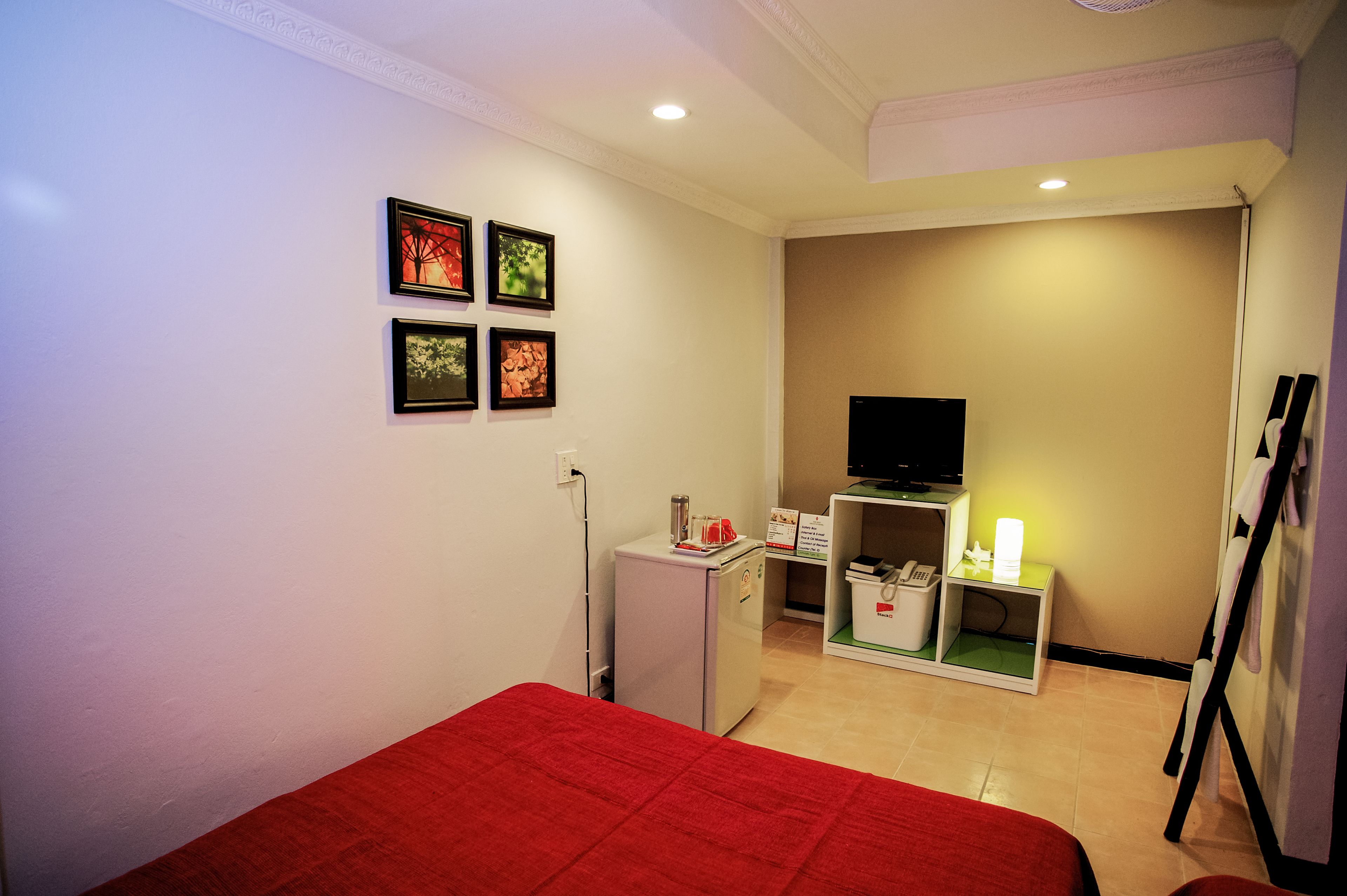 A hotel room with a bed, a small refrigerator, a television, and a desk with a chair.