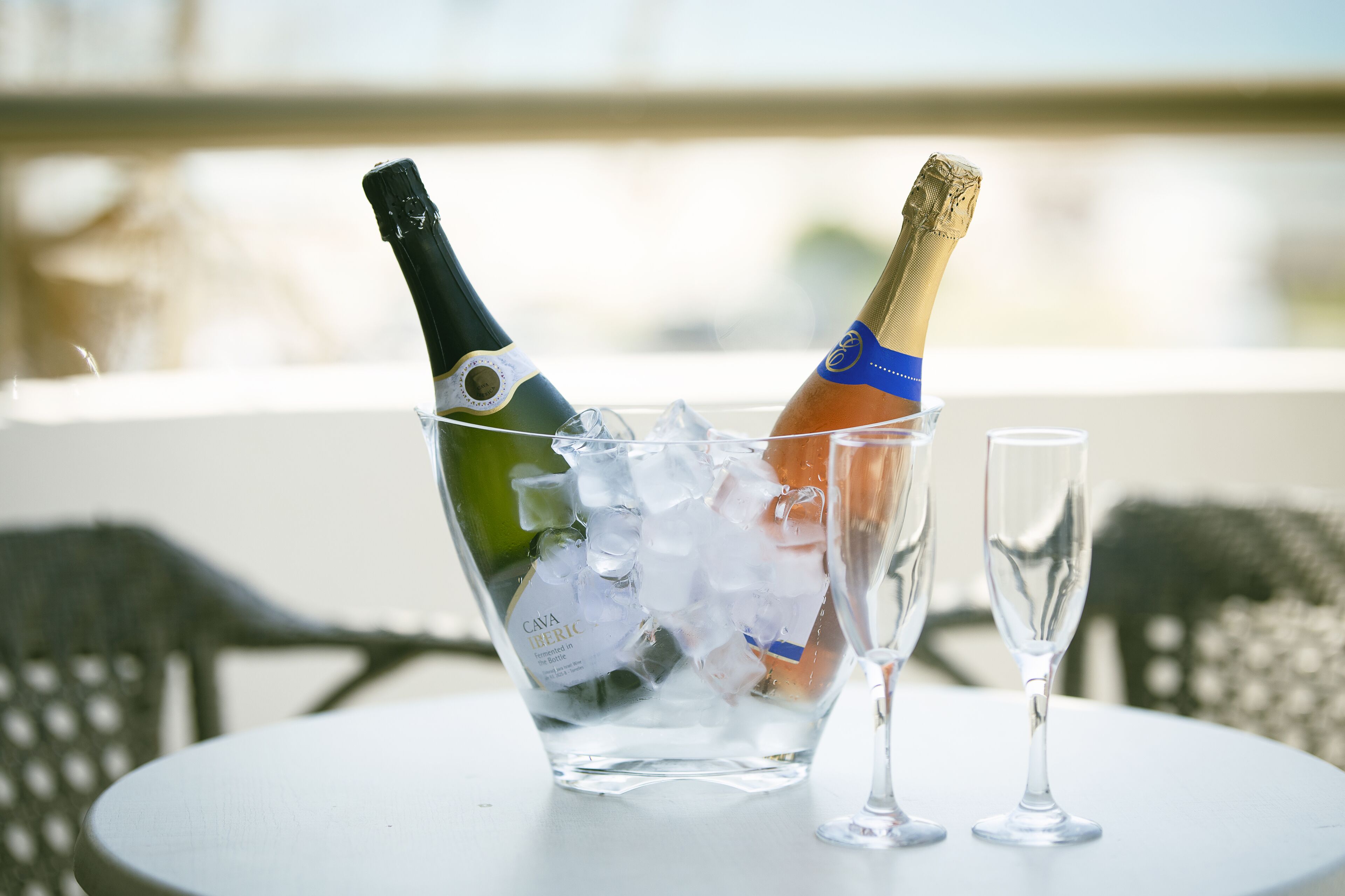 Ein Tisch mit einer Glaskaraffe, zwei Champagnerflaschen und einem Glas.