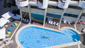 An aerial view of a hotel with a swimming pool surrounded by lounge chairs and umbrellas. - Marine Heights Suites (Herzliya)