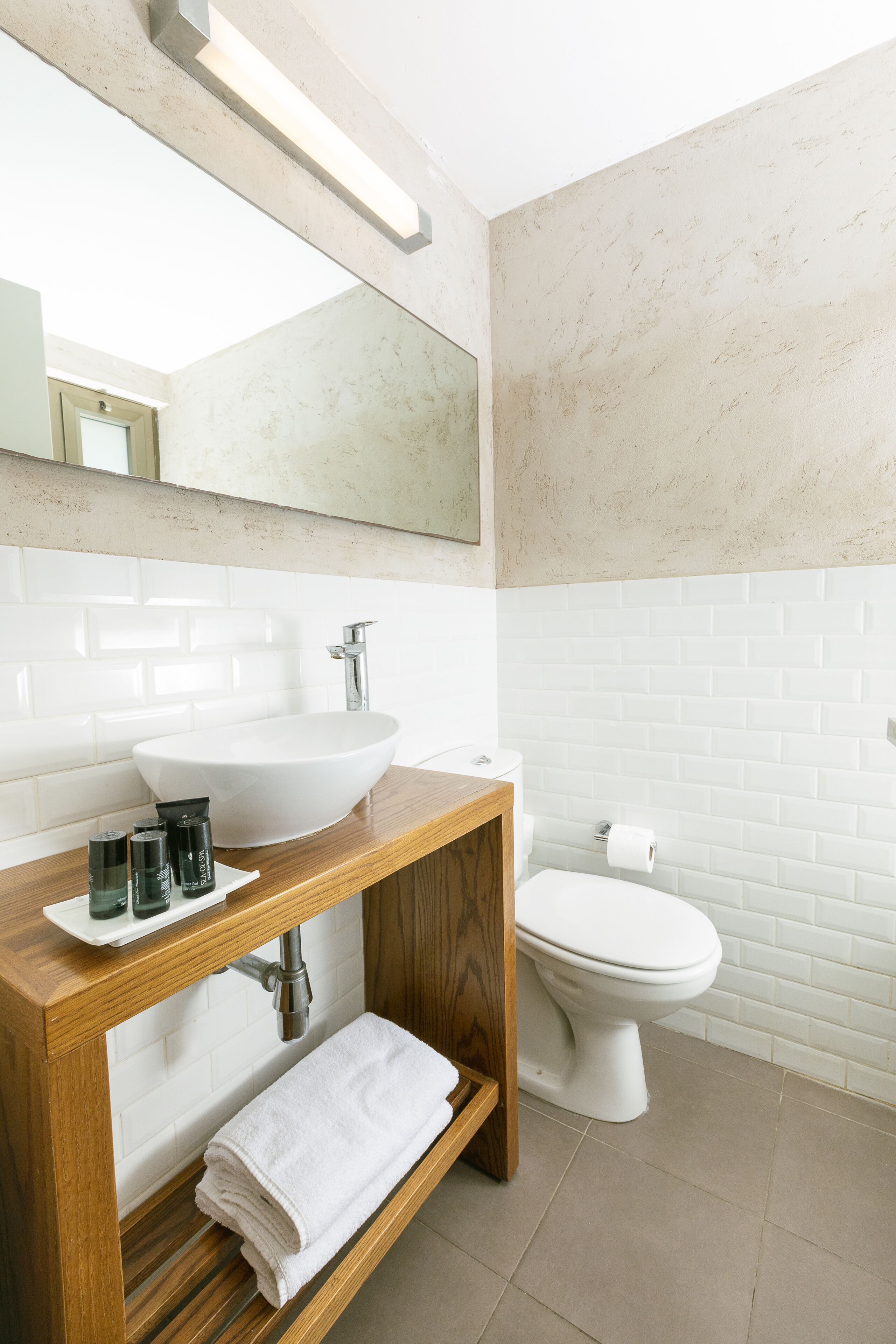 Un baño moderno con tocador de madera, lavabo blanco y un inodoro.