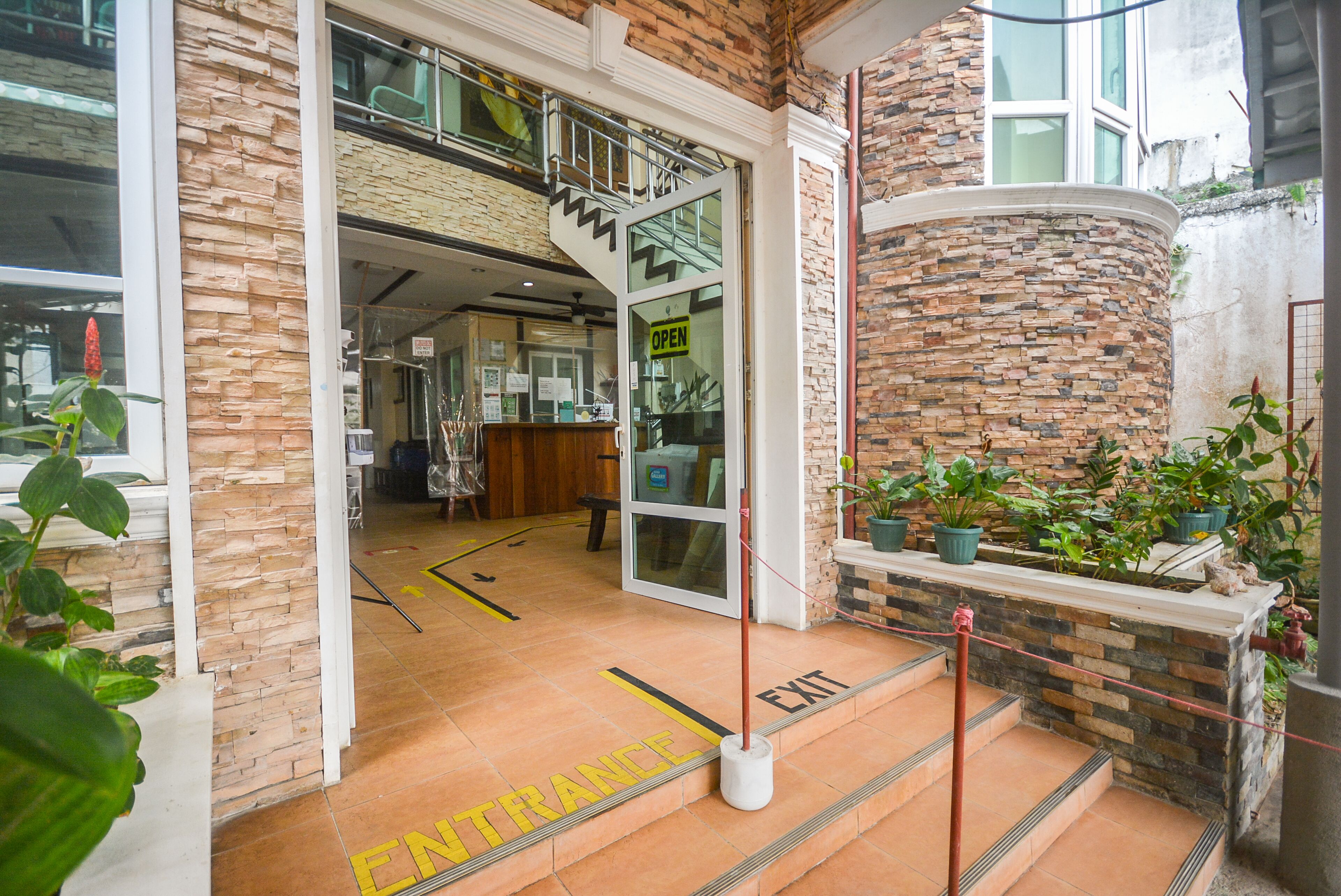 Fachada de hotel de piedra, entrada abierta y escalera que conduce a los pisos superiores.