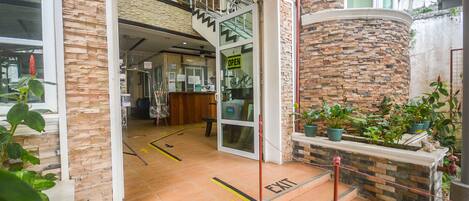 Fachada de hotel de piedra, entrada abierta y escalera que conduce a los pisos superiores.