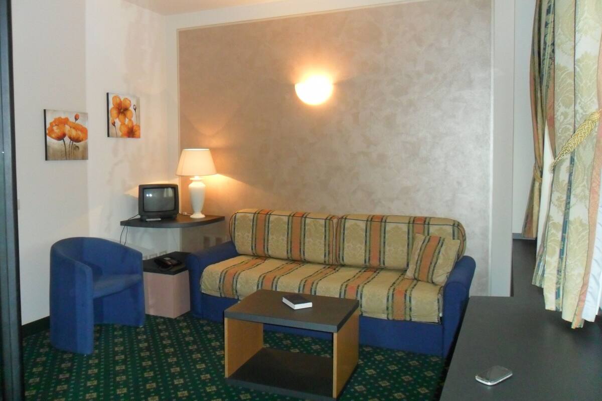 A small, cozy living room with a sofa, a coffee table, a TV, and a lamp.