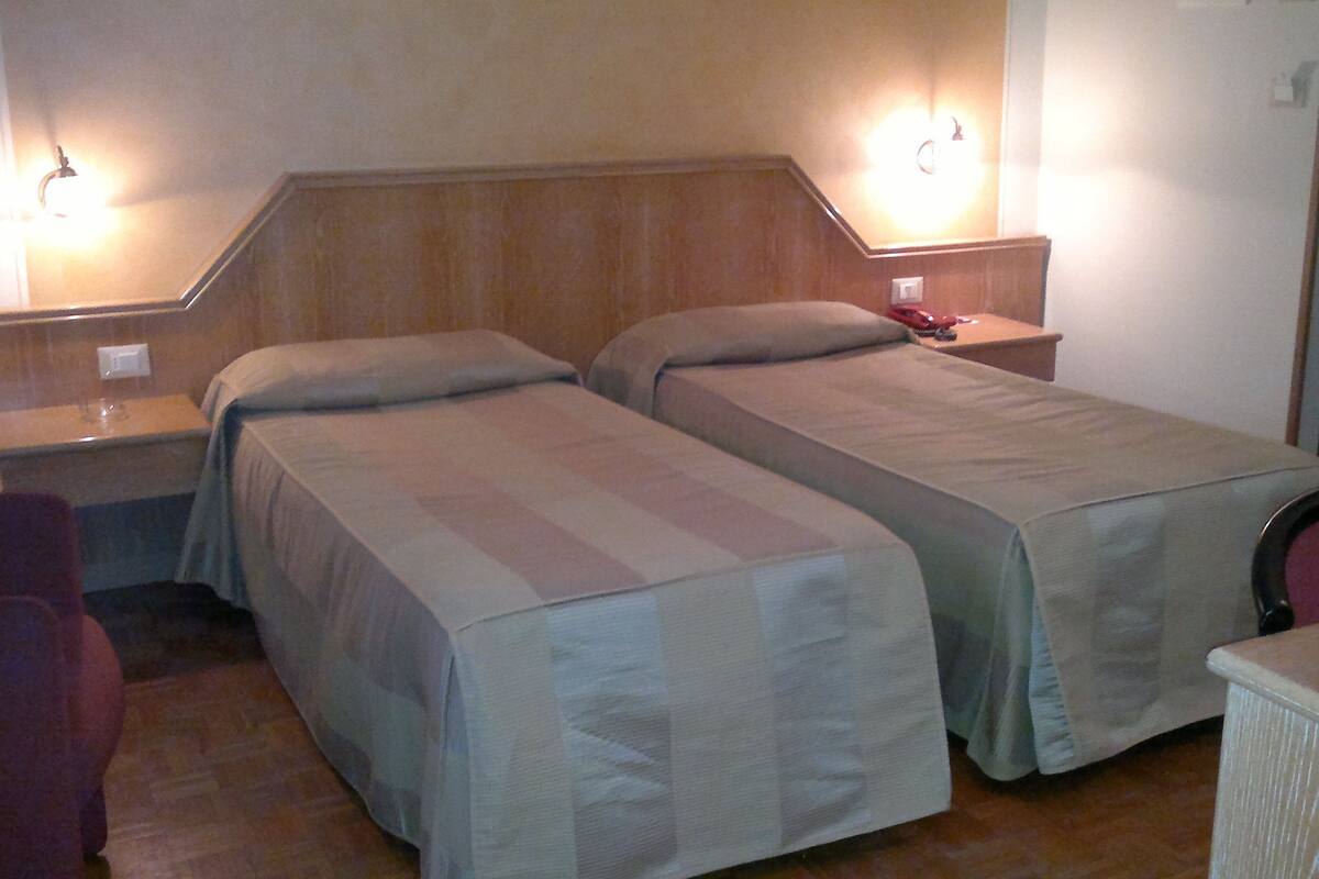 A room with two single beds, a nightstand, a chair, and a desk.