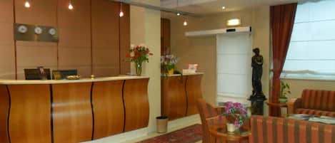 A hotel lobby with a reception desk, seating area, and a statue.