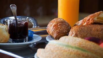 Ett frukostbricka med croissanter, en smörgås och ett glas juice.