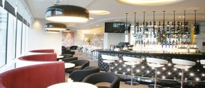 Eine Barbereich mit verschiedenen Sitzgelegenheiten, einer Bar und einem Fernseher.