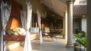 A spacious indoor area with a sofa and chairs, a dining table, and a large window with curtains. - Villa Pakem (Pakem)