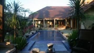 A pool area with a covered seating area and potted plants.