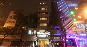 A building with multiple floors, a karaoke bar on the ground floor, and various signs and advertisements on the facade.