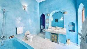 A bathroom with a blue wall, a bathtub, a shower, a toilet, and a sink with a mirror.