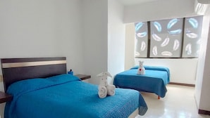 Habitación de hotel con dos camas, una mesita de noche, una toalla y un ventanal con motivos de hojas.