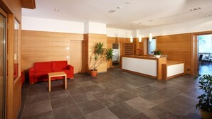 Un área de recepción moderna con un mostrador de madera, un sofá rojo y una planta en maceta.