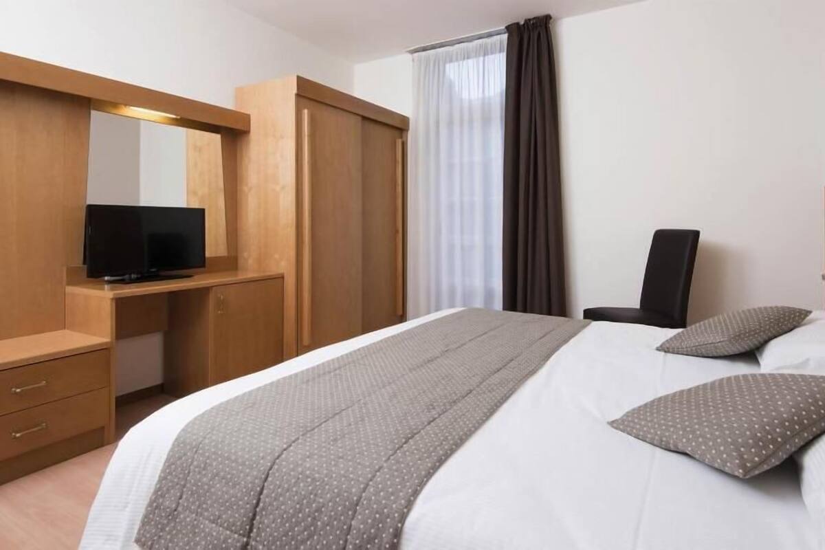 A hotel room with a bed, a TV, a desk, and a wardrobe.