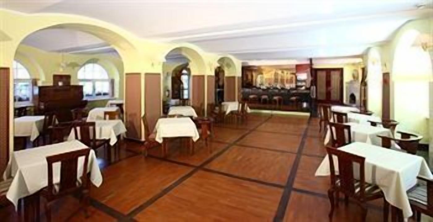 A spacious dining area with multiple tables and chairs, high ceilings with arched windows, and a central open space.