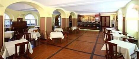 A spacious dining area with multiple tables and chairs, high ceilings with arched windows, and a central open space.