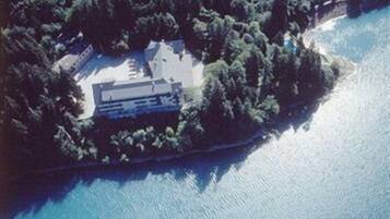 Une vue aérienne d’une île isolée, avec un seul bâtiment entouré d’une forêt dense.