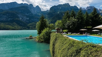 Una piscina al aire libre, sombrillas, sillones reclinables de piscina