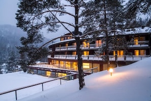 Un edificio de varios pisos con balcones, rodeado de árboles cubiertos de nieve.