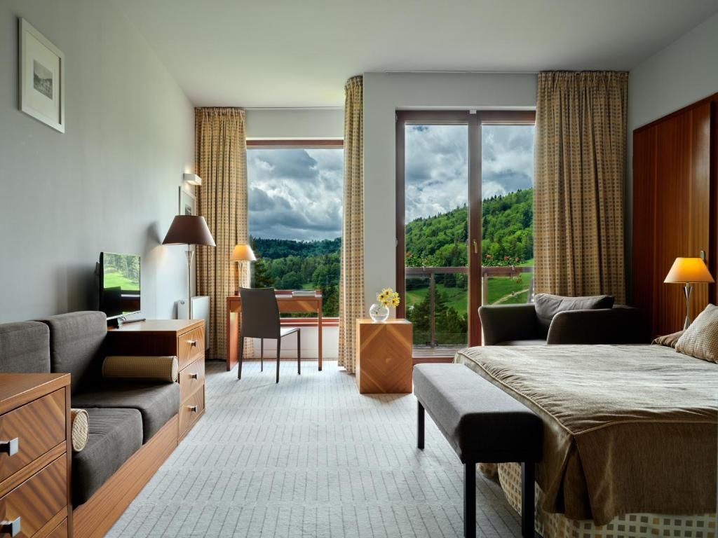 Une chambre d’hôtel équipée d’un lit, d’un bureau, d’une chaise, d’une télévision et offrant une vue sur un paysage montagneux.
