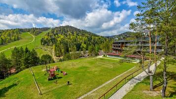 Hotel com vista para um campo verde e uma montanha ao fundo.
