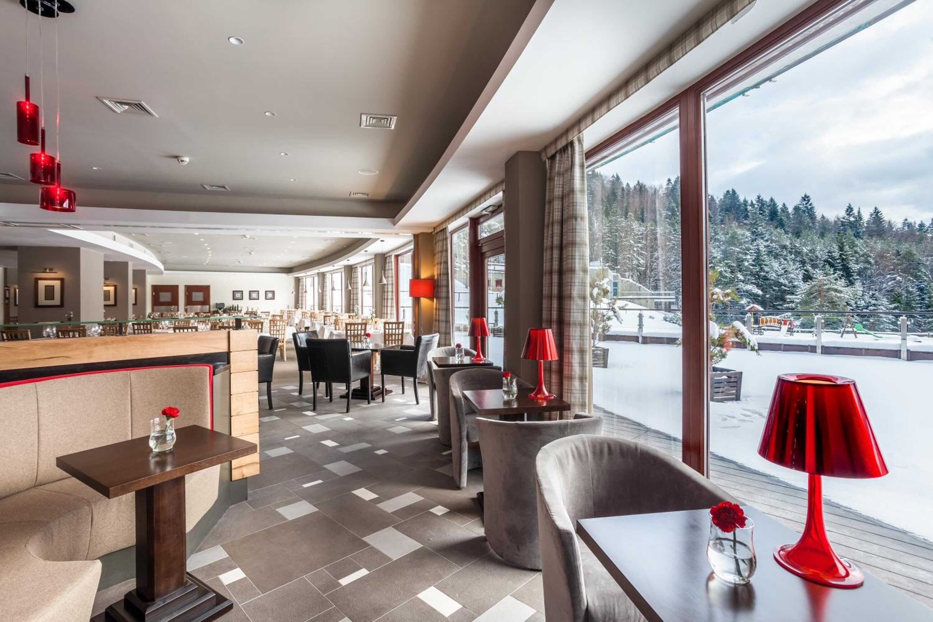 A modern hotel lobby with a bar area, seating arrangements, and large windows offering a view of a snowy landscape.