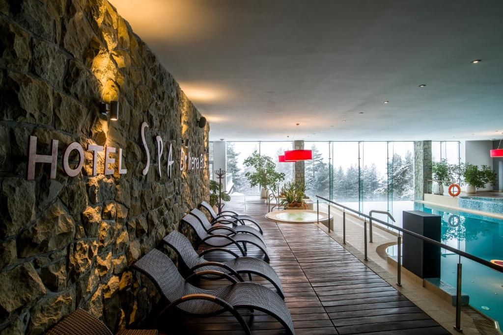 A hotel lobby with a stone wall, seating area, and a pool view.