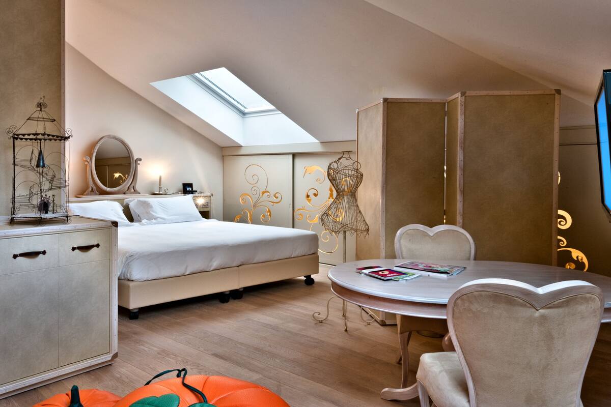 A modern bedroom with a skylight, a bed, a desk with a chair, and a wardrobe.