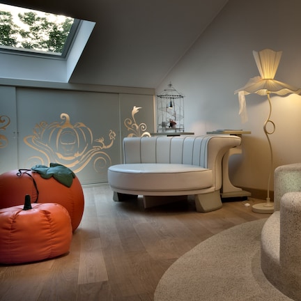 A modern bathroom with a freestanding bathtub, a round seating area, and a unique wall design.