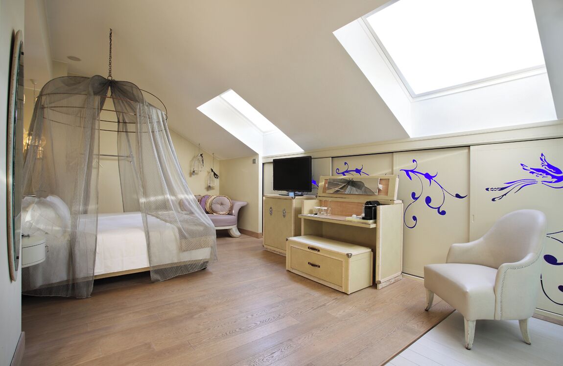 Een slaapkamer met hemelbed, bureau, stoel en televisie.