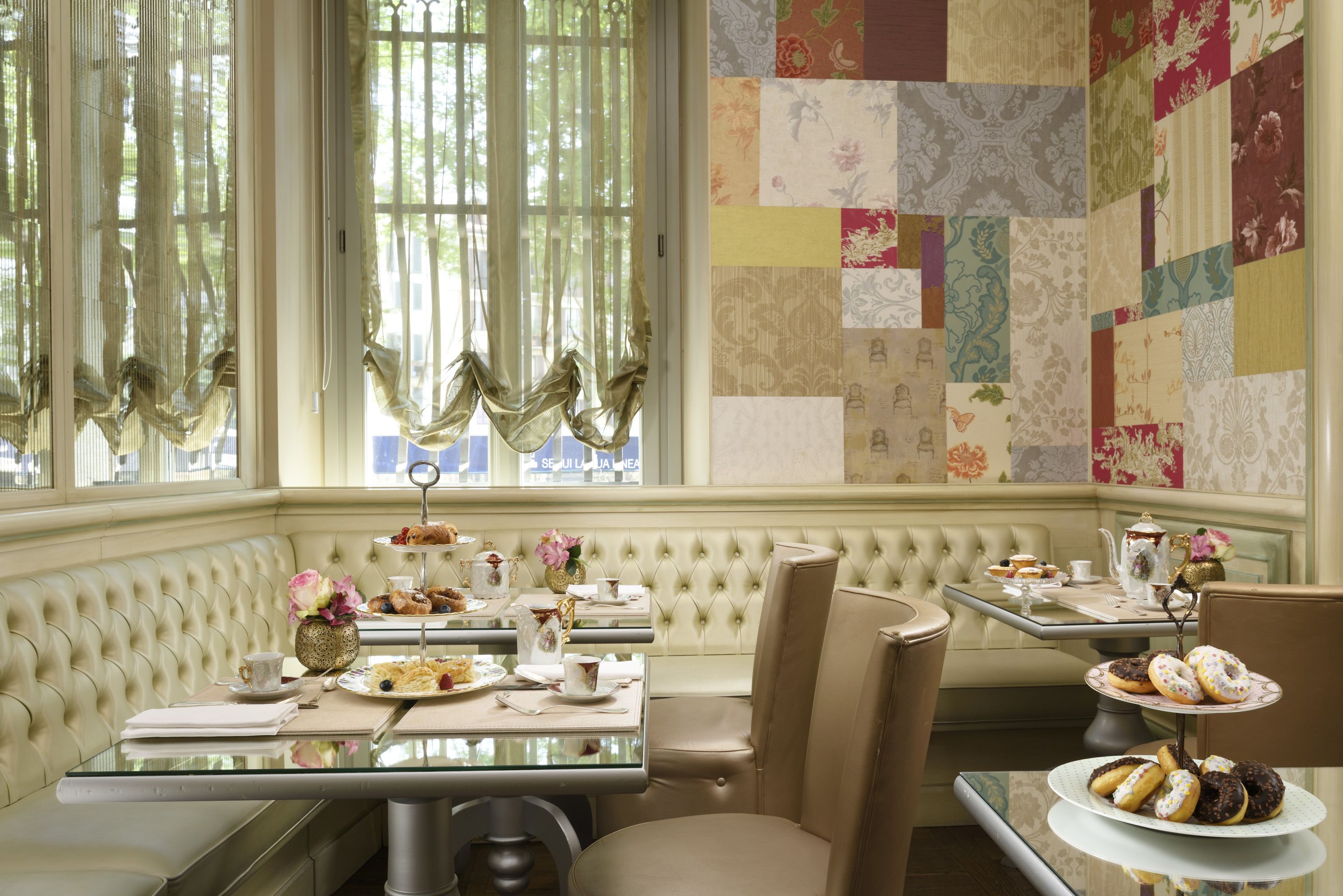 A cozy dining area with a cushioned bench, a glass table, and a quilted wall.