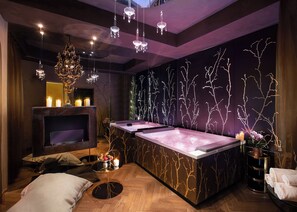 A modern spa room with a wooden floor, a large bathtub, and a wall with tree branch designs. - Château Monfort (Milan)