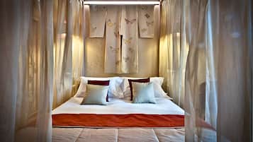Una cama impecable con sábanas blancas y un detalle rojo, rodeada de cortinas traslúcidas con estampado de mariposas.