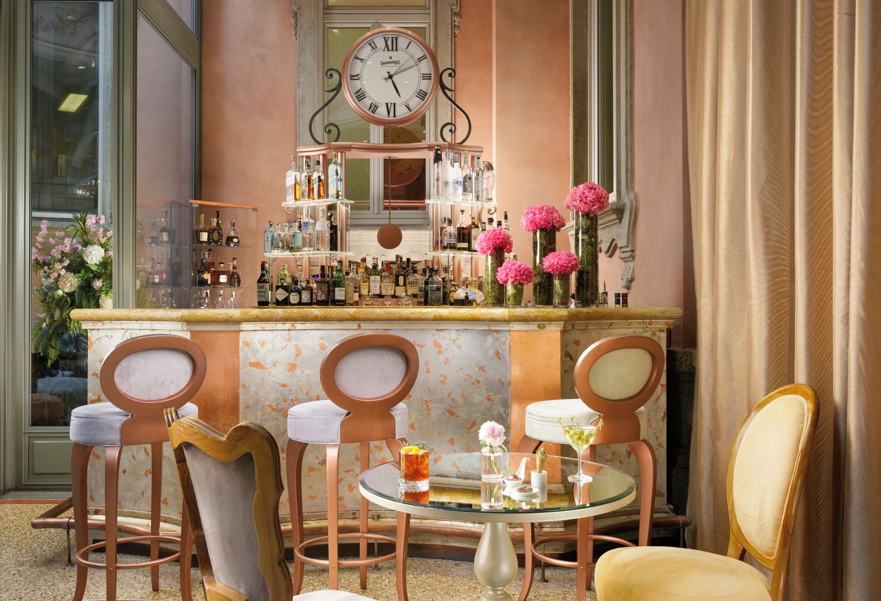 Eine Bar mit einer Uhr, Barhocker und einem runden Tisch mit Getränken.