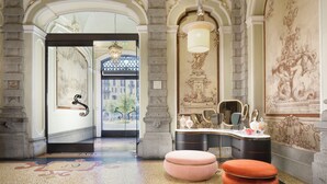 A grand lobby with ornate architecture, a large mirror, and a decorative bench. - Château Monfort (Milan)